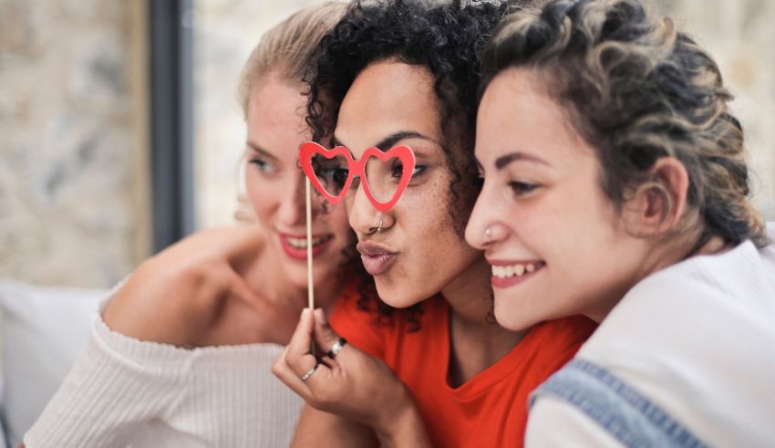 A group of women are taking a picture with a heart shaped stick.
