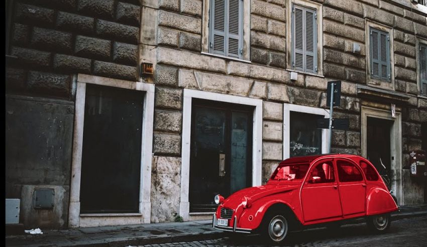 A red car is parked in front of a building.