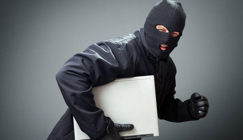 A thief holding a laptop on a gray background.