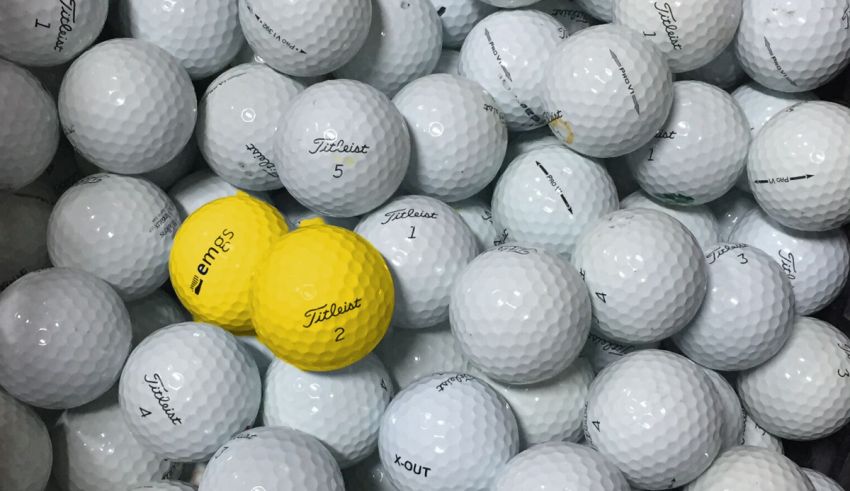 A pile of golf balls with a yellow ball in the middle.