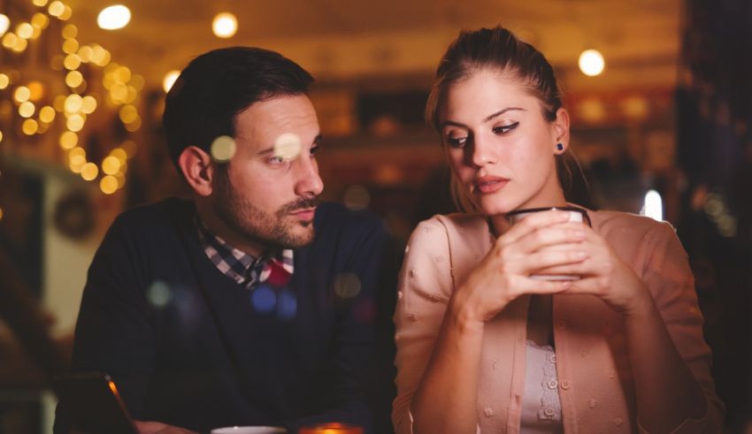 A man and woman sitting at a table looking at a tablet.