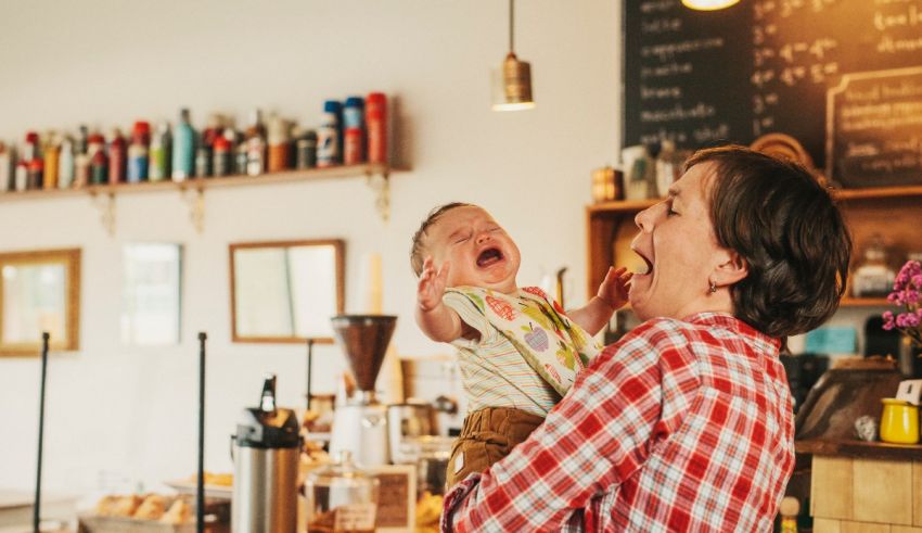 A woman holding a baby in a coffee shop.