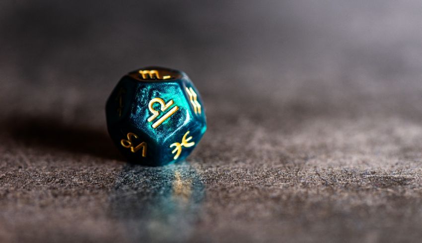 A blue and gold dice sits on a dark surface.