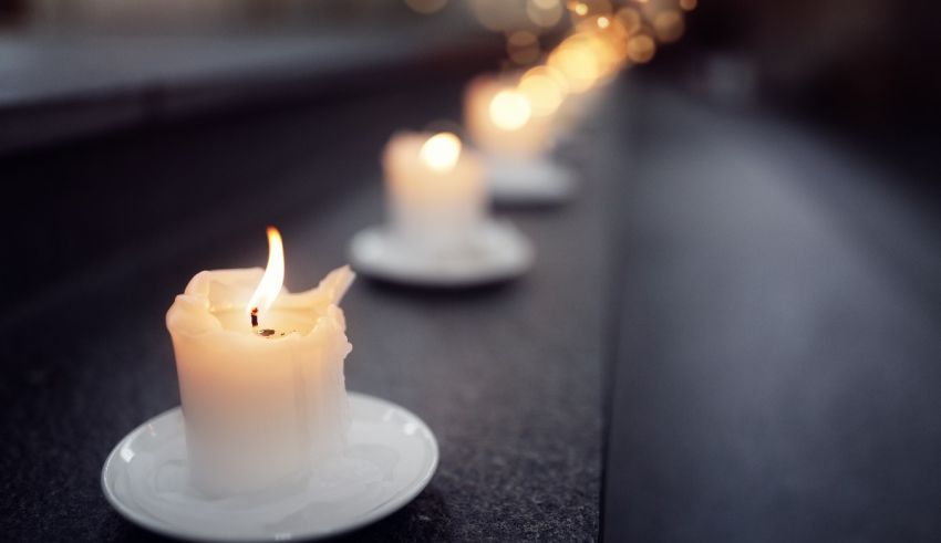 A row of candles on a table in front of a wall.