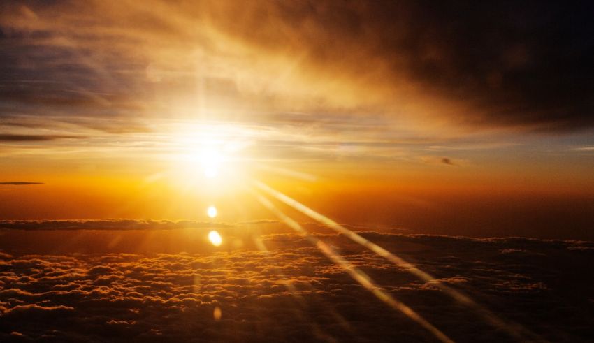 The sun rises over the clouds from an airplane.
