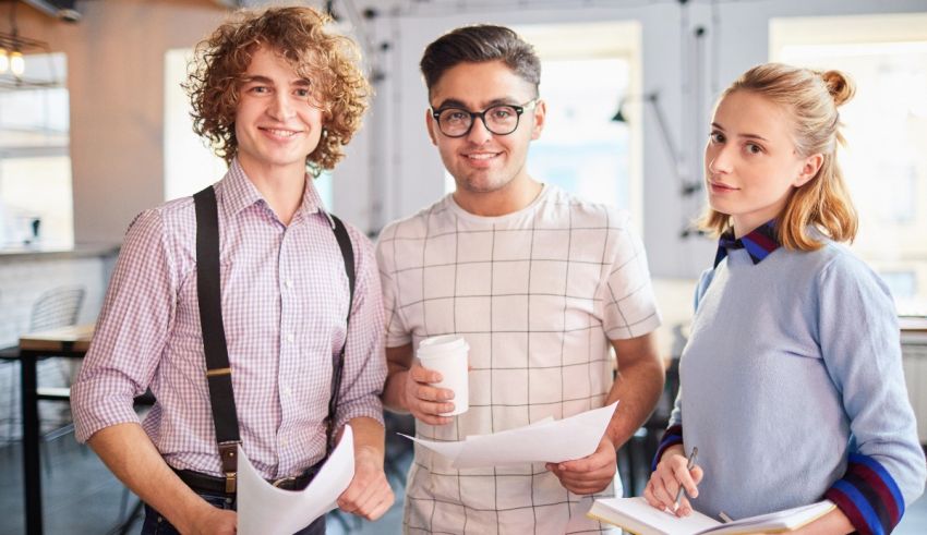 Three young people holding papers in a cafe.