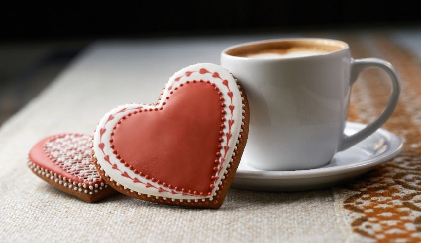 Two heart shaped cookies and a cup of coffee.