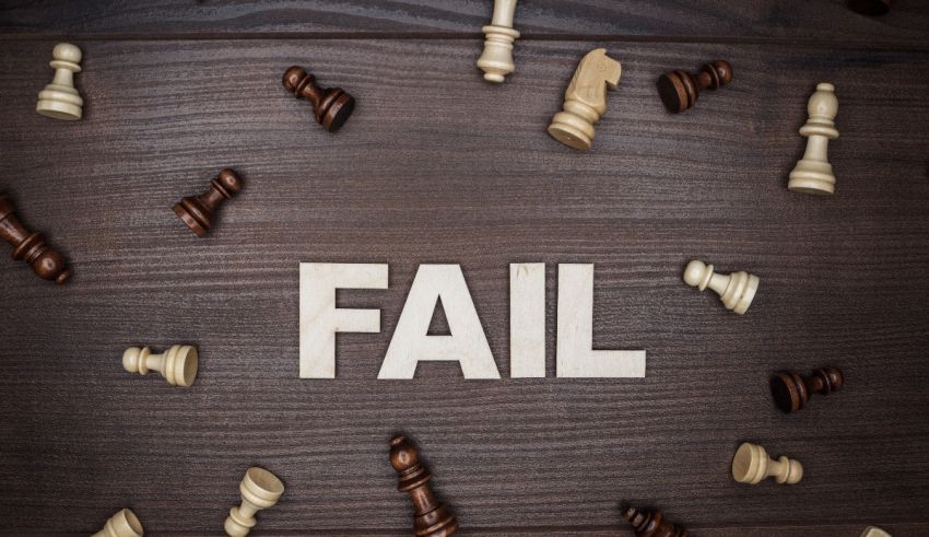 The word fail surrounded by chess pieces on a wooden table.