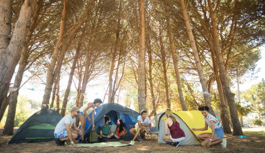 A group of people sitting around a tent in a forest.