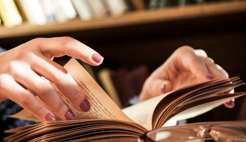 A woman is reading a book in a library.