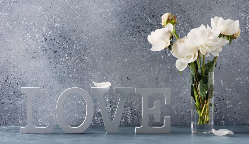 White flowers in a vase next to the word love.