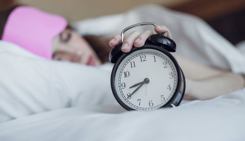 A woman sleeping with an alarm clock on her head.