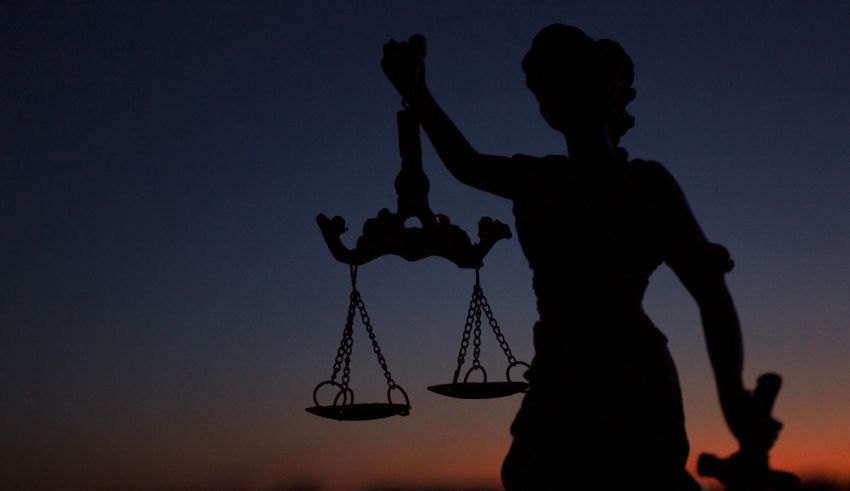 A silhouette of a woman holding the scales of justice at sunset.