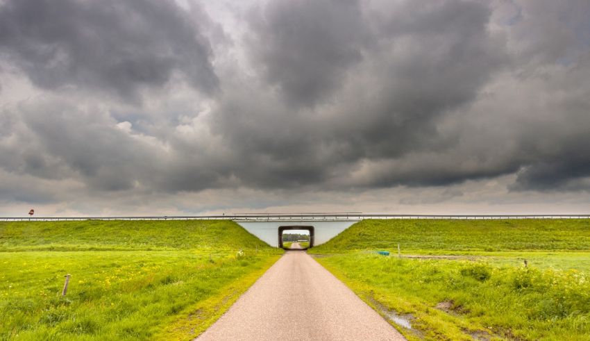 A road with a bridge under a cloudy sky.