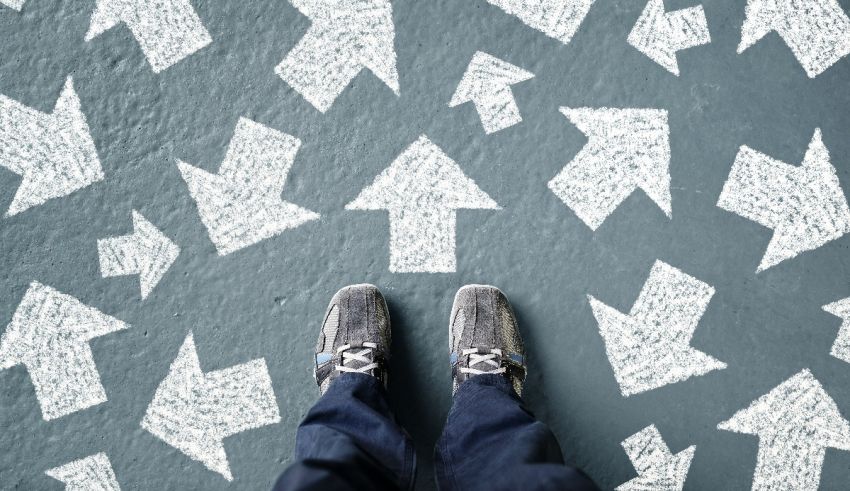 A person's feet standing in front of arrows.