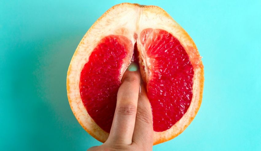 A person's hand is holding a grapefruit on a blue background.