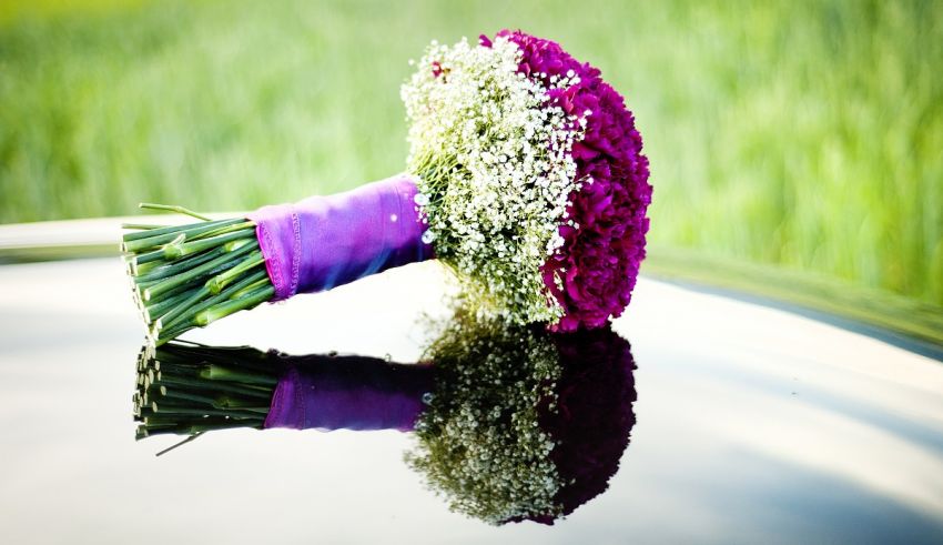 A bouquet of purple and white flowers is reflected in the reflection of a car.