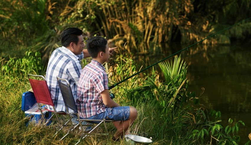 Two men sitting on chairs and fishing in a river.