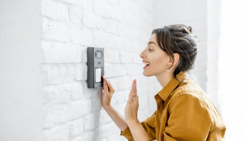 A woman is looking at a doorbell on a brick wall.