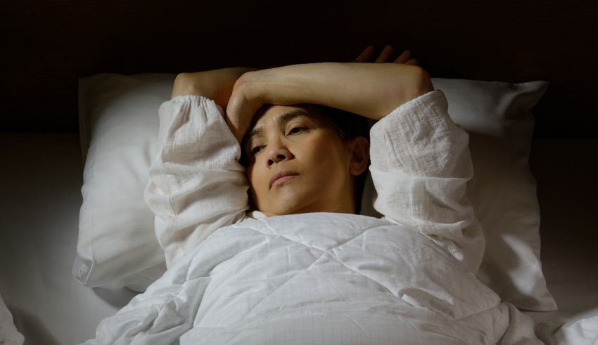 A woman laying in bed with her head resting on her hand.