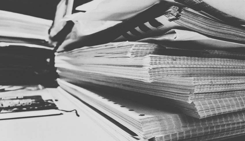 Black and white photo of a pile of papers on a desk.