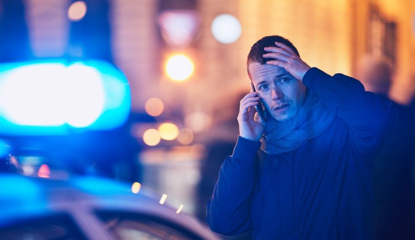 A man talking on a cell phone in front of a police car.