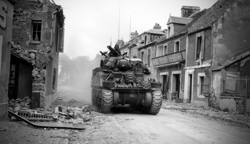 Black and white photo of a tank driving down a street.