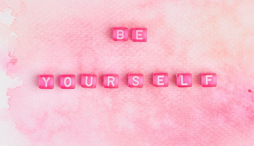 The word be yourself written on a pink watercolor background.