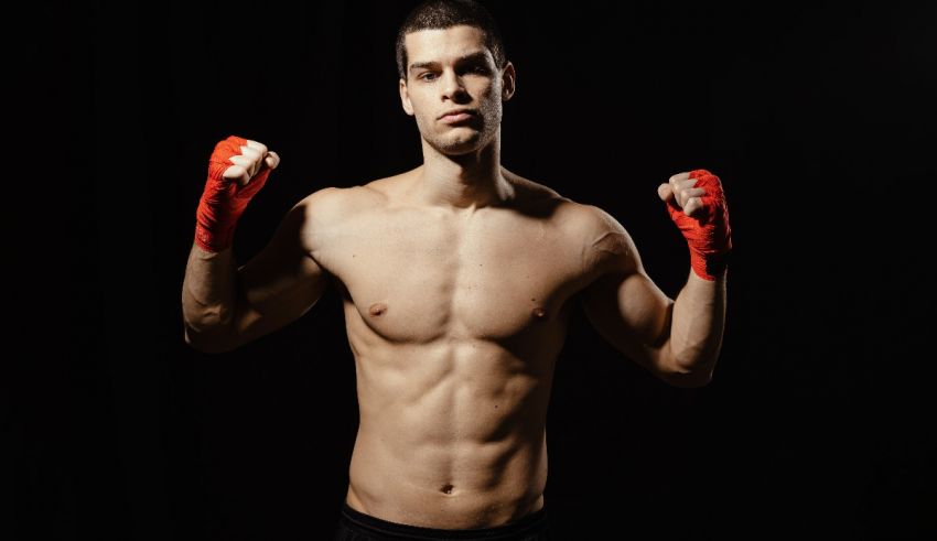 A man in boxing gloves posing on a black background.