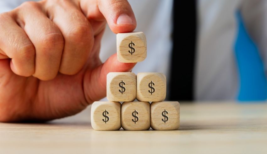 A businessman holding a stack of wooden cubes with dollar signs on them.