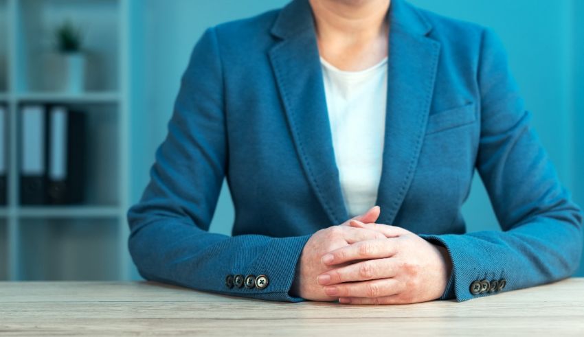 A business woman sitting at a table with her hands folded.
