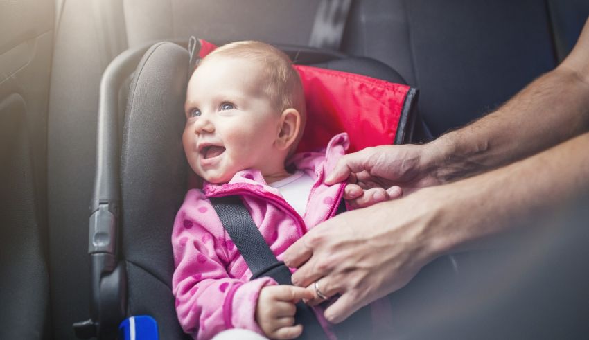 A baby is being strapped into a car seat.