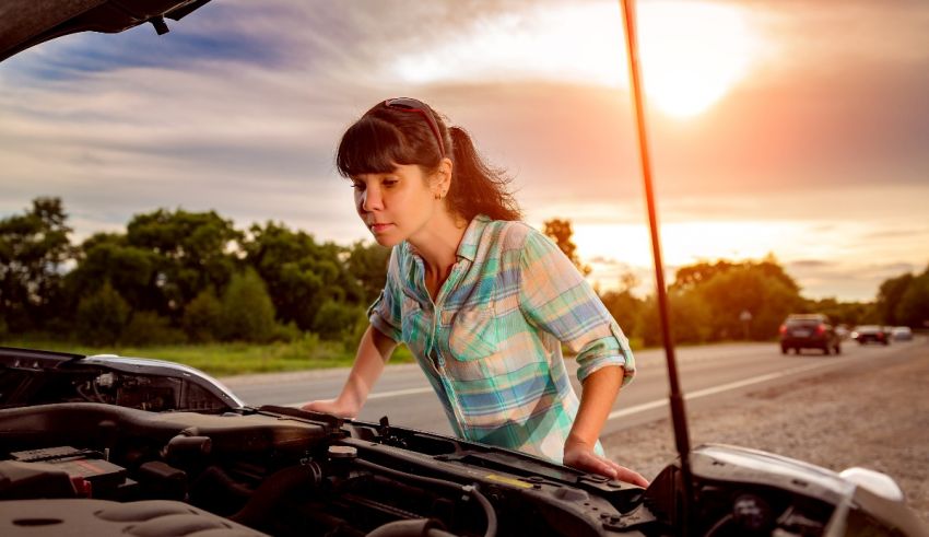 A woman looking at the hood of her car.