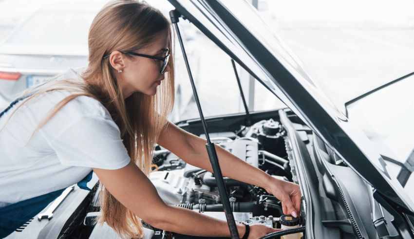 A woman working on the engine of a car.