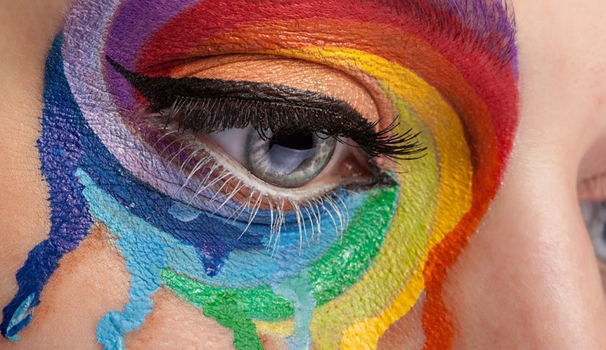 A close up of a woman's eye with a rainbow painted on it.