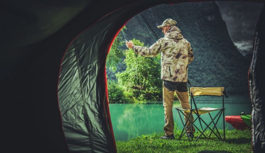 A man is fishing out of a tent.