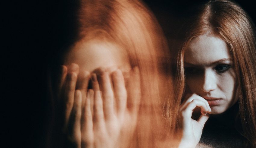 A woman with red hair is holding her face in front of a mirror.