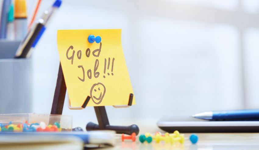 A sticky note with the word good job on it on a desk.