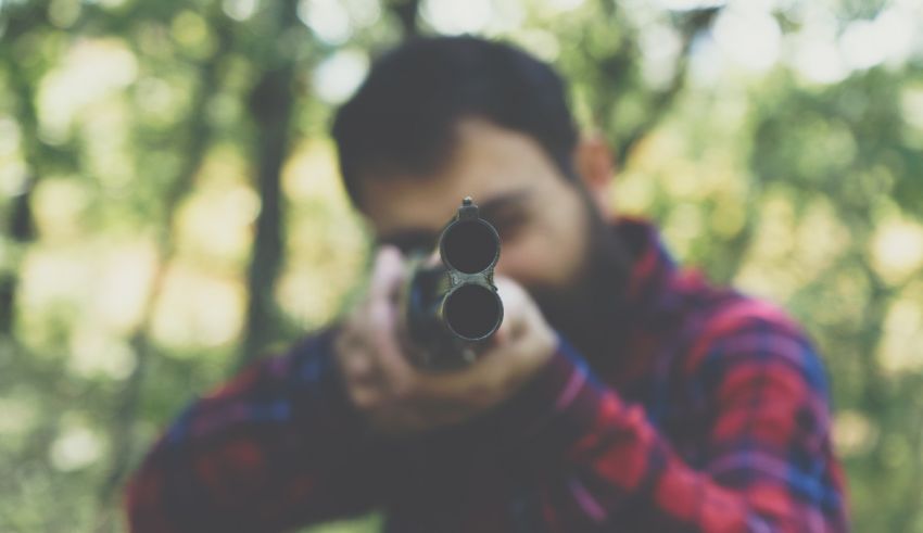 A man is holding a gun in the woods.