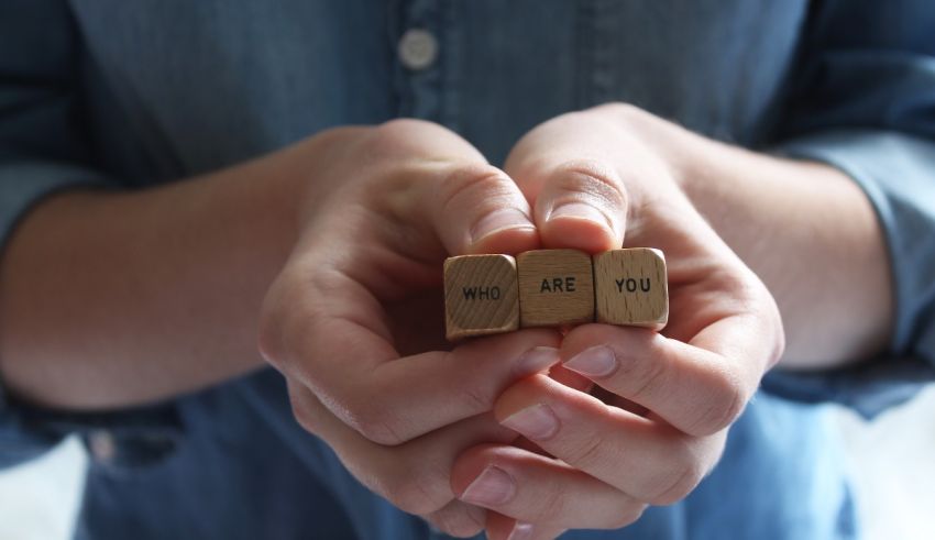 A woman's hands holding two wooden cubes that say i am you and i am you.