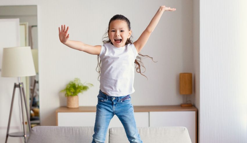 A young girl jumping on a couch in her living room.