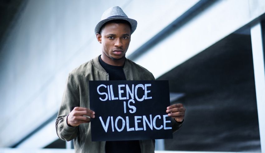 A man holding up a sign that says silence is violence.