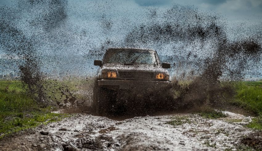 A jeep driving through mud on a dirt road.