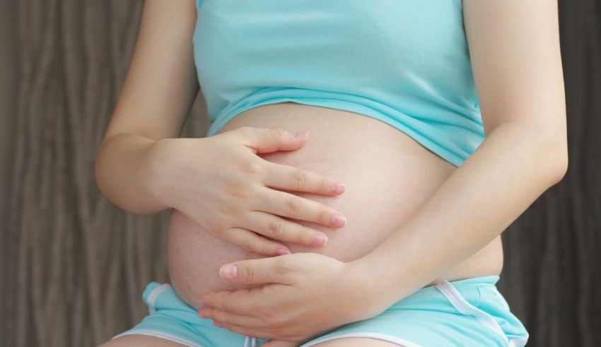A pregnant woman is holding her stomach.