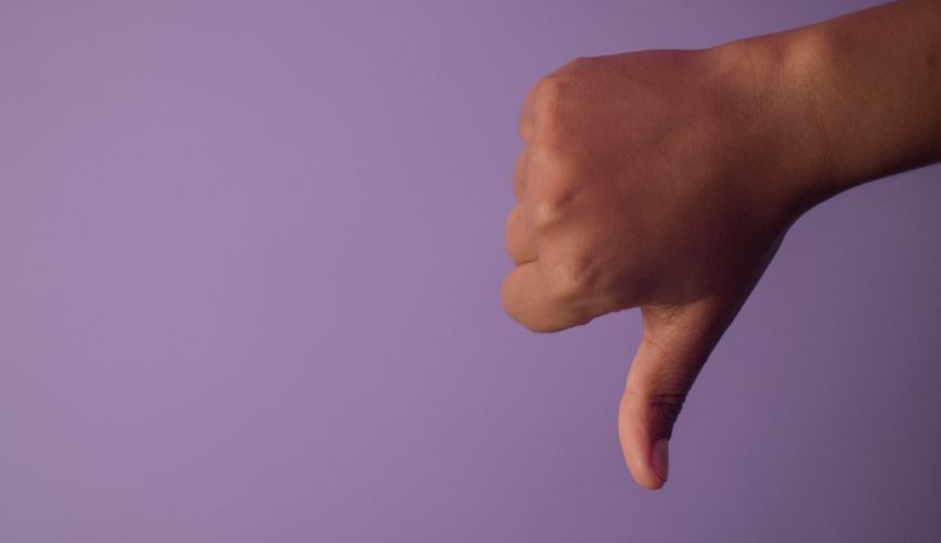 A hand with a thumbs down sign on a purple background.