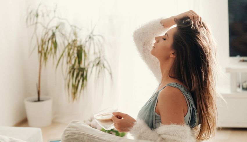 A woman is sitting on a couch in front of a plant.