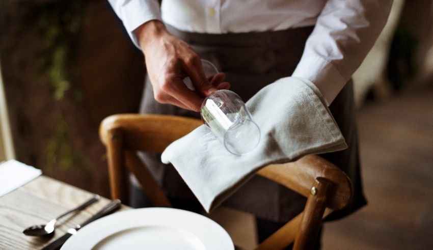A waiter putting a napkin on a table.