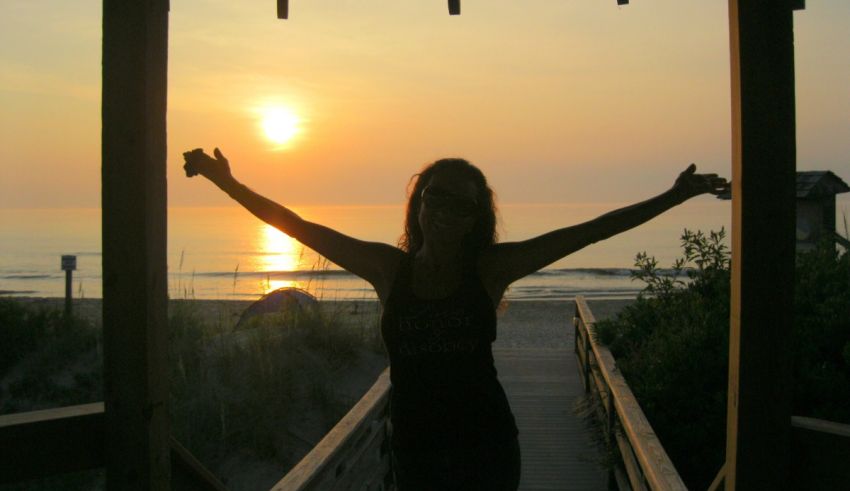 A woman standing on a pier with her arms outstretched.