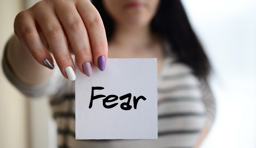 A woman holding up a piece of paper with the word fear on it.