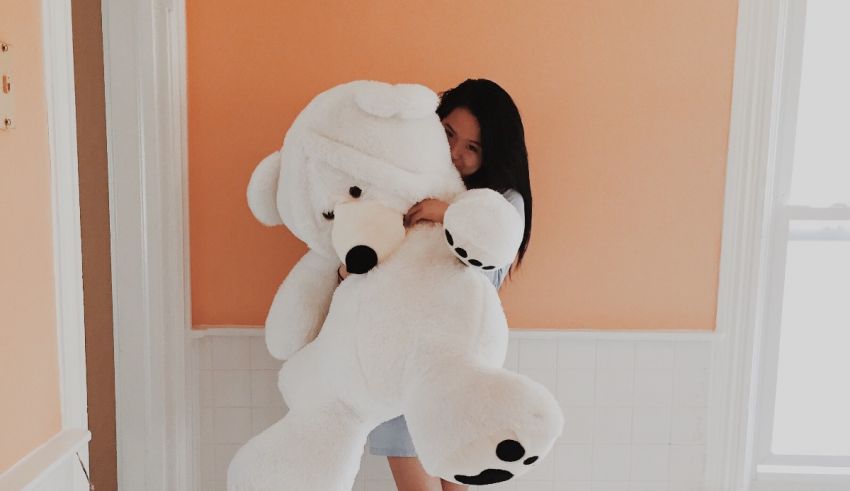 A woman is hugging a large white teddy bear.